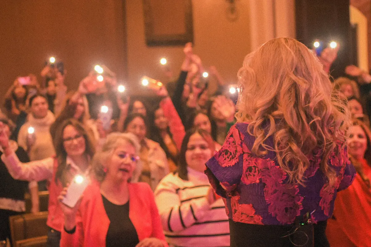 El público ilumina el salón con sus celulares mientras Adriana Macías habla